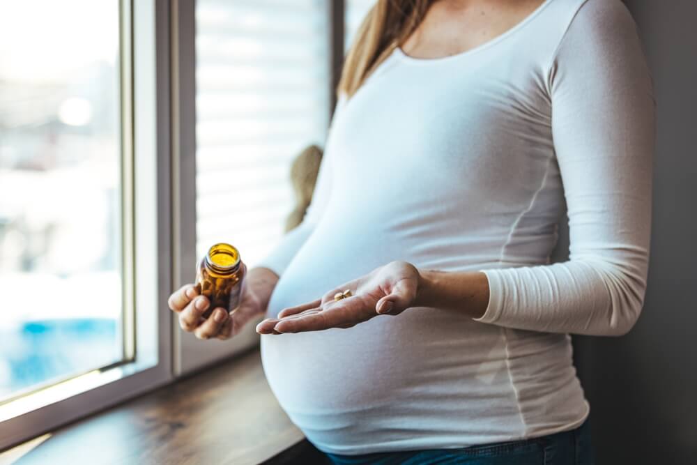 trudnica drži bočicu prenatalnih vitamina