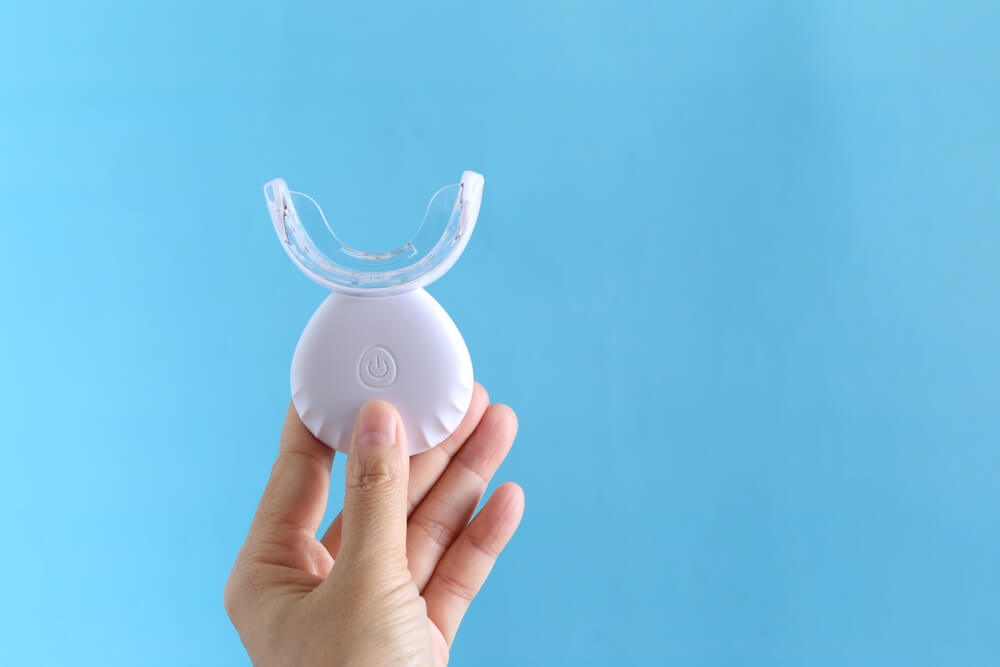 devojka drži u ruci hello smile led aparat za izbeljivanje zuba